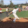 Pitcher winds up to throw to catcher while campers and coaches watch