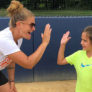 Coach and camper high five in front of backstop