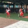 Softball players practice hitting technique in batting cages