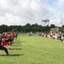 Softball players pair up in the grass to practice throwing while on one knee