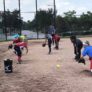 Softball players practice fielding in partners