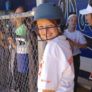 Camper smiles with helmet on just outside dugout